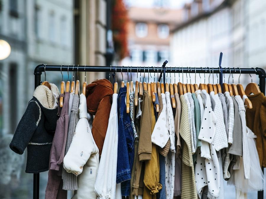 Arara com roupas infantis em tons claros e neutros penduradas em cabides.